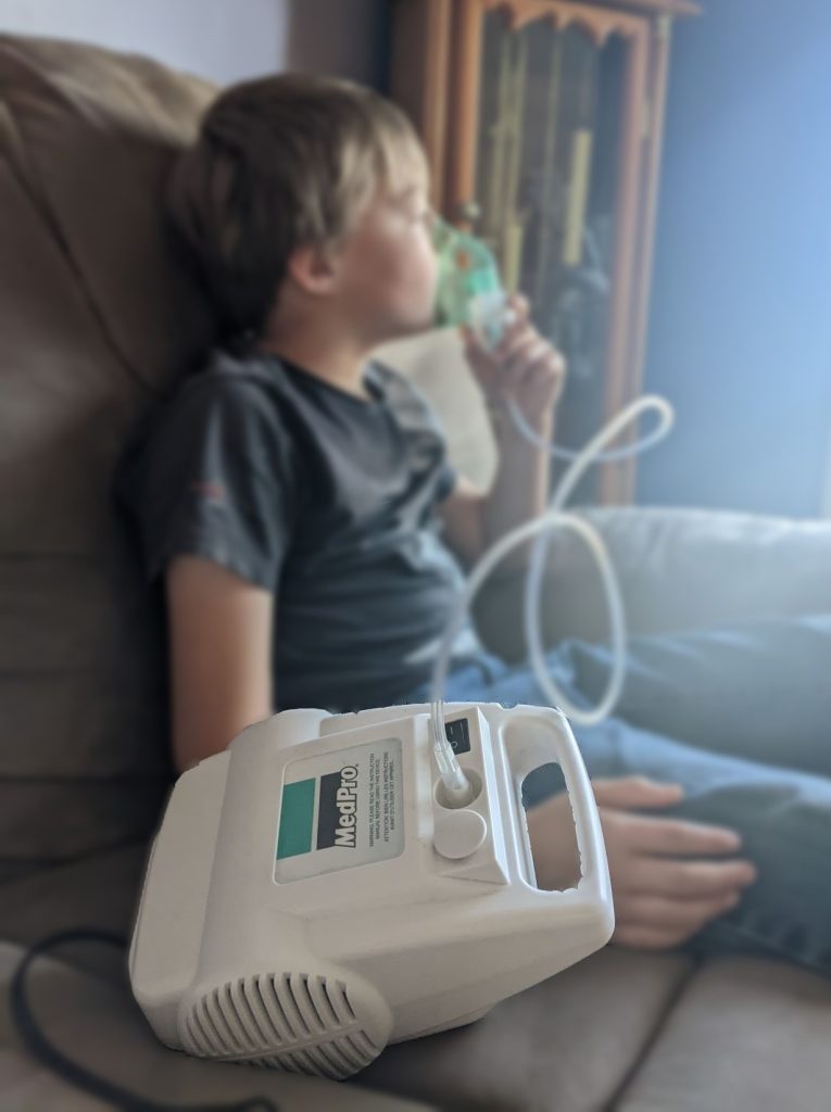 boy sitting on a couch using a nebulizer