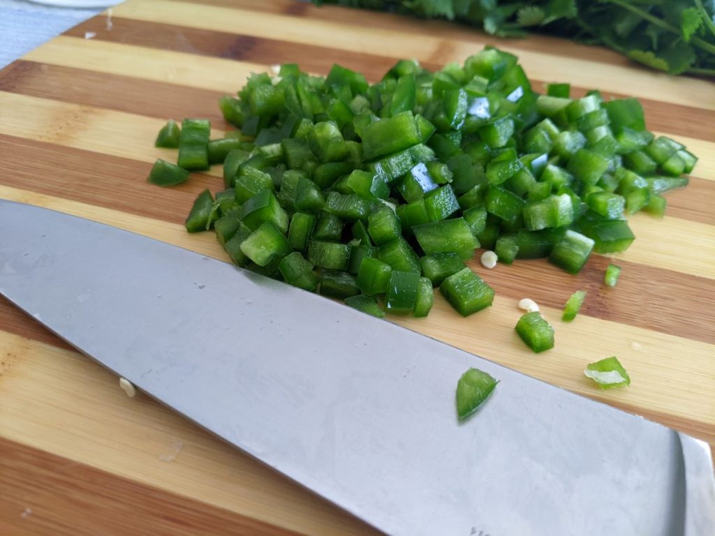 chopped jalapenos on a cutting board with a knife