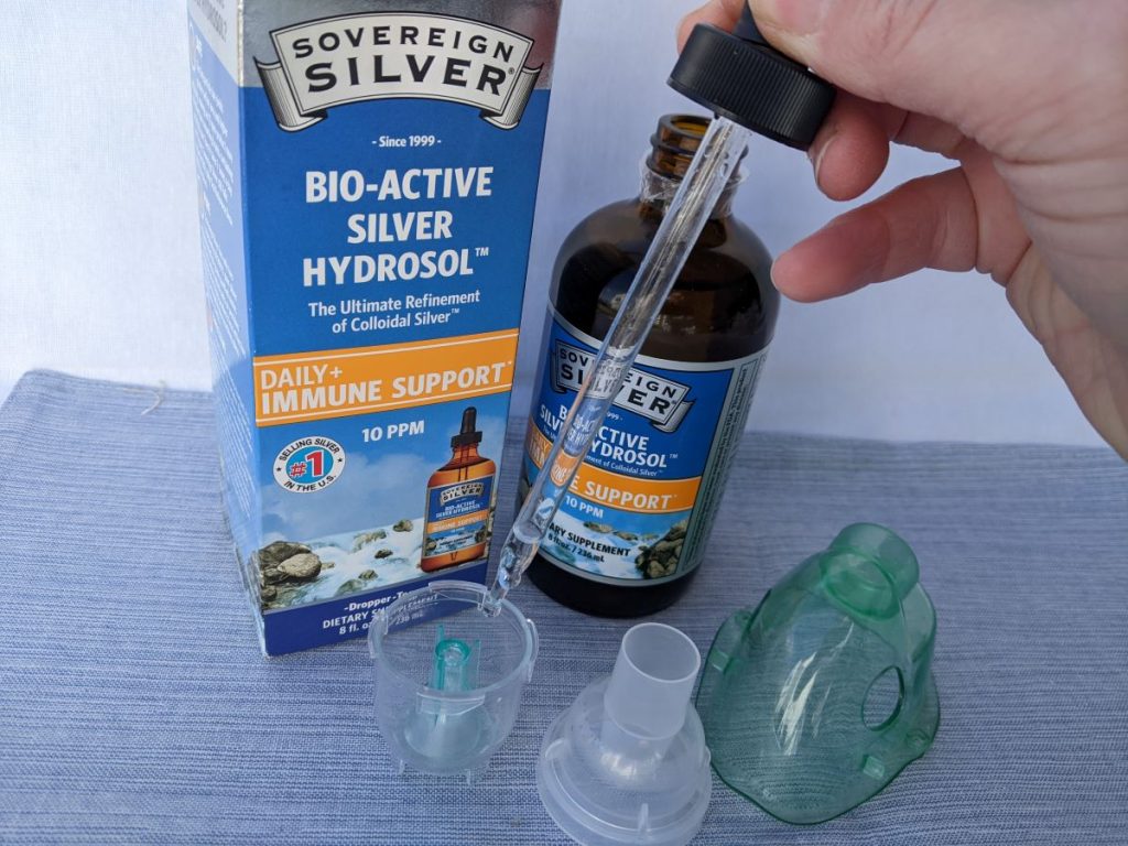 hand holding a medicine dropper putting sovereign silver into nebulizer cup