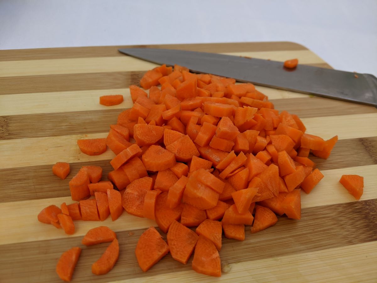 chopped carrots on a cutting board with a knife