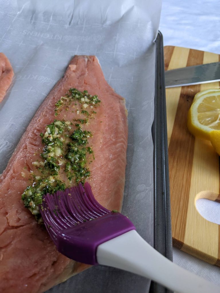 Salmon being brushed with a seasoning paste