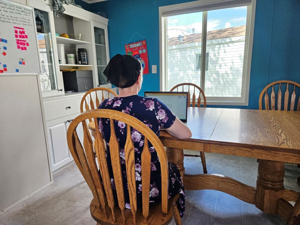back of a woman sitting at a table with a laptop
