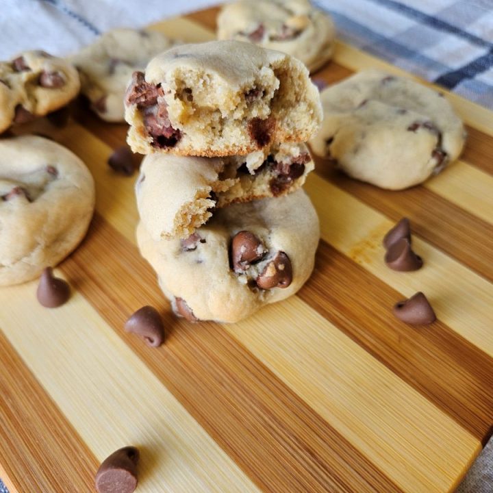 chocolate cream cheese cookies on a cutting board with chocolate chips sprinkled around in