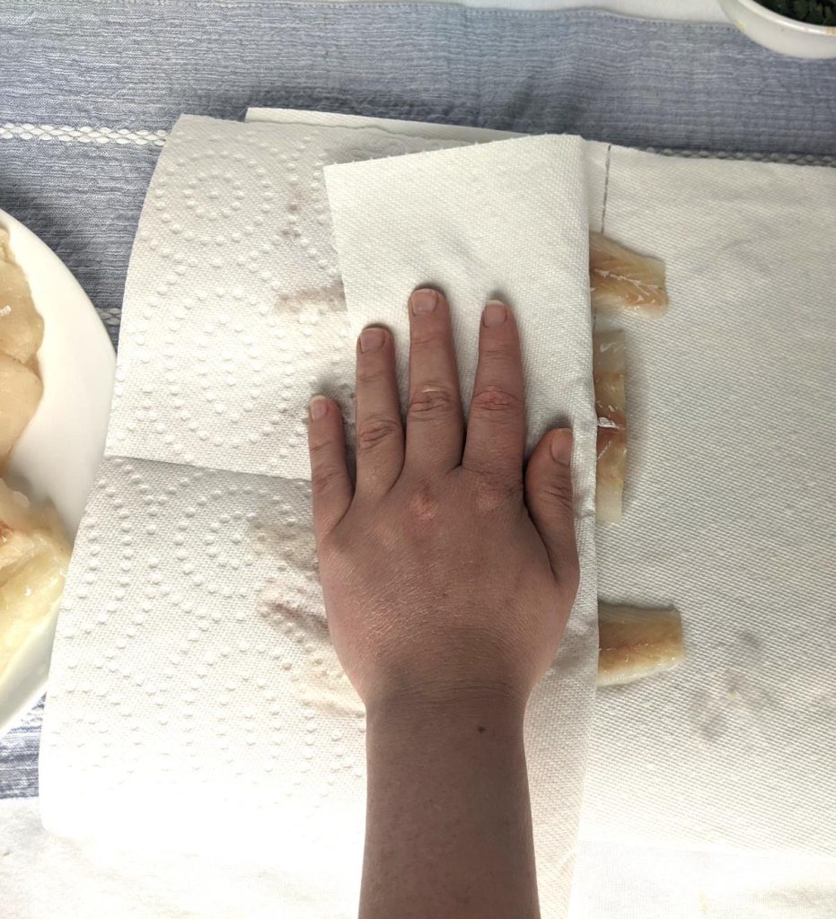 cod wrapped in a paper towel being dried