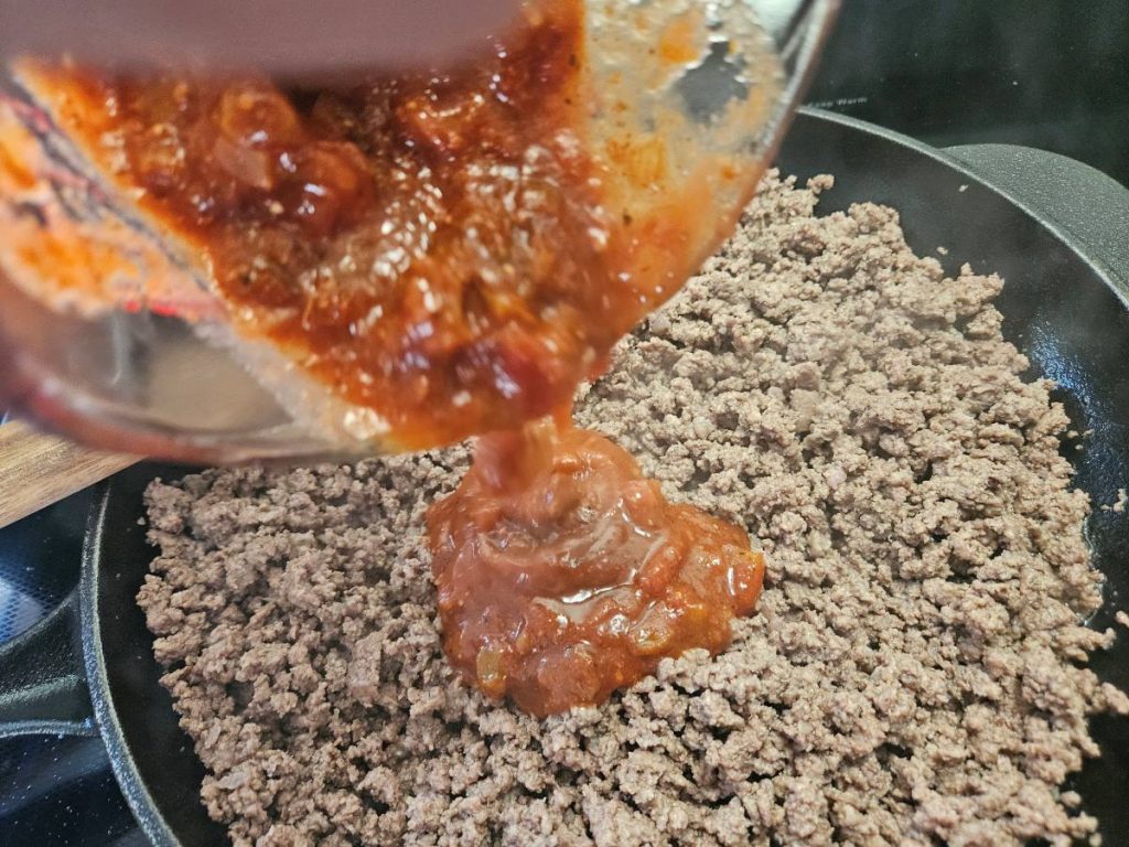 salsa and taco seasoning being poured on taco meat