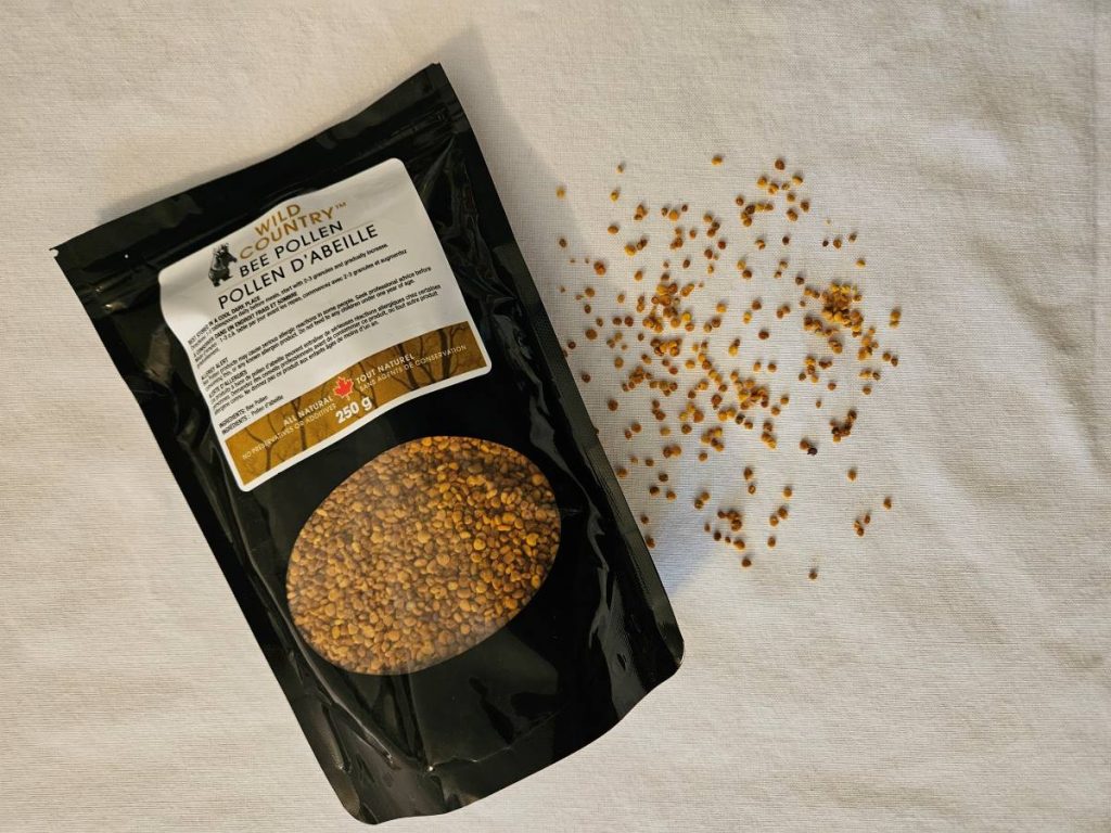 A bag of be pollen laying on a table with bee pollen pellets spread out beside it. 