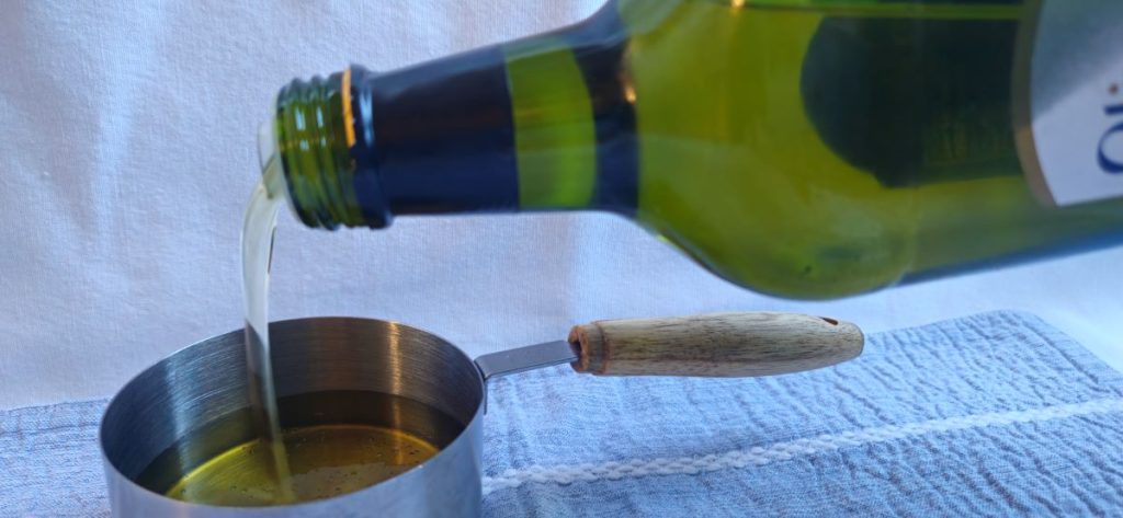 Avocado oil being poured into a measuring cup.
