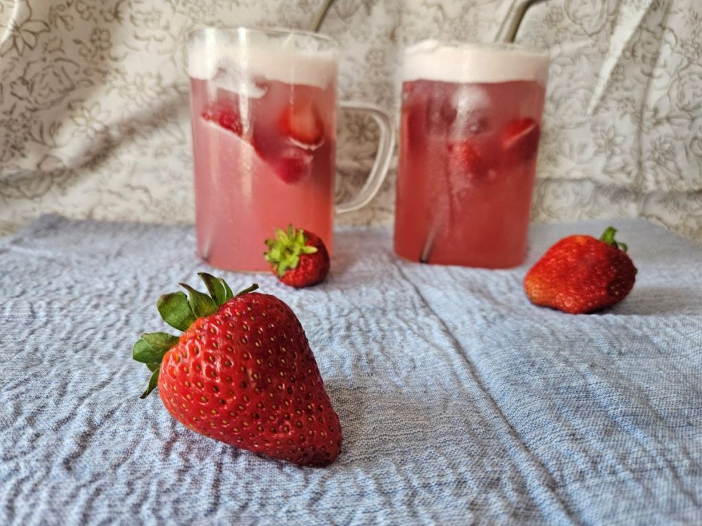 Strawberry with two cups of pink drink in the backround